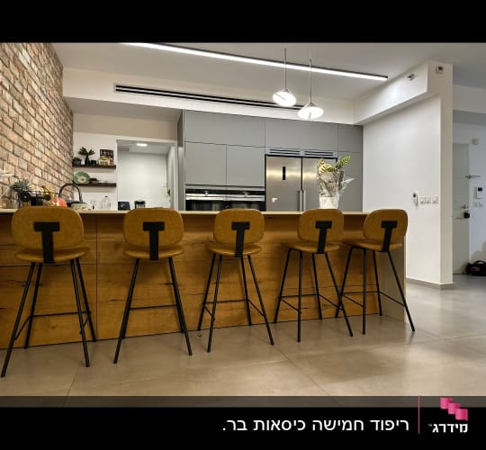 חמישה כיסאות בר מרופדים מול דלפק עץ במטבח מודרני